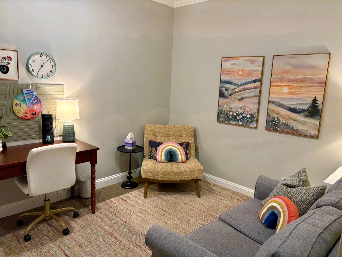 Therapy room from the other side, showing the desk, a feelings wheel and a clock on the wall
